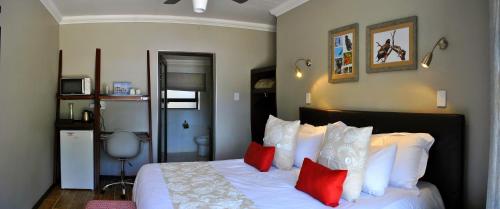 a bedroom with a bed with red and white pillows at Christie's Inn in Tzaneen