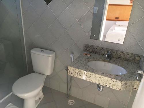 a bathroom with a toilet and a sink and a mirror at Pousada Aruana Praia in Aracaju