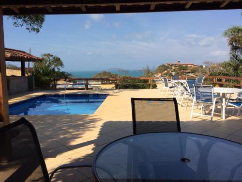 a patio with a table and chairs and a pool at Praia da Ferradurinha Guest House in Búzios