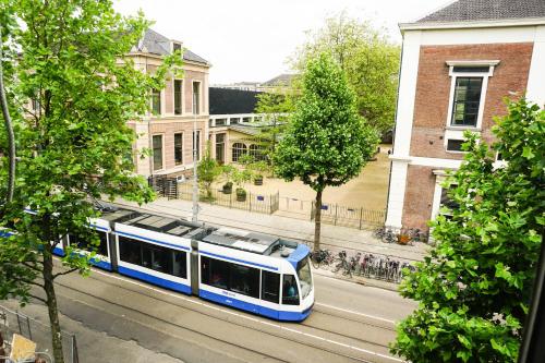 a blue and white train on a city street at De Jonker Urban Studios & Suites in Amsterdam