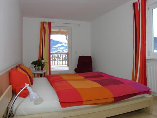 a bedroom with a bed with a colorful blanket and a window at "schön-urlauben" in Gröbming