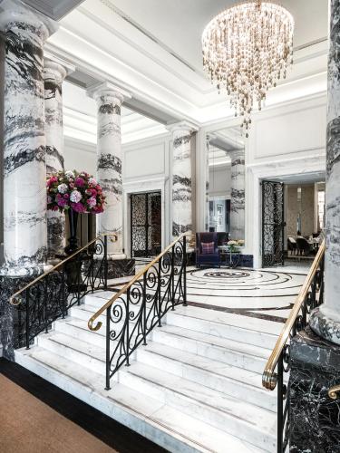 a lobby with a staircase and a chandelier at The Langham London in London