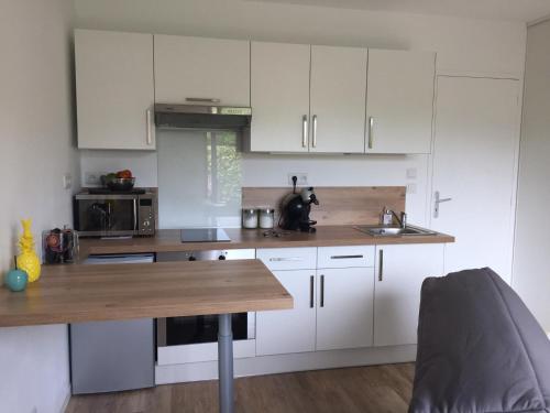 a kitchen with white cabinets and a wooden counter top at Casa Tagomago in Andernos-les-Bains