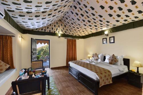 a bedroom with a large bed and a ceiling at Kumbhalgarh Safari Camp by Trulyy in Kumbhalgarh