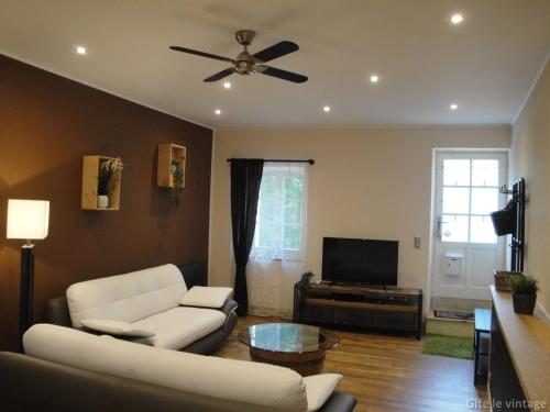 a living room with a couch and a ceiling fan at Gîte Le Vintage in Saint-Émilion