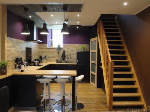 a kitchen with purple walls and a kitchen island with bar stools at Gîte Le Vintage in Saint-Émilion