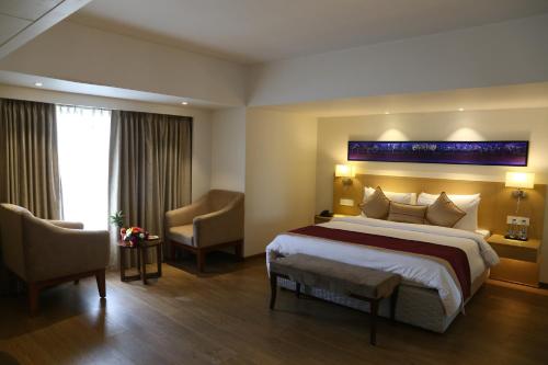 a hotel room with a large bed and a chair at Sarovar Portico Rivera Ahmedabad in Ahmedabad