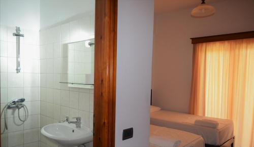 baño pequeño con lavabo y cama en JB Hotel, en Sarandë