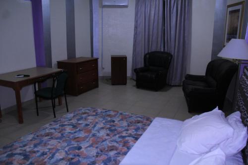 a hotel room with a bed and a desk and chairs at Massao Palace Hotel in Yaoundé
