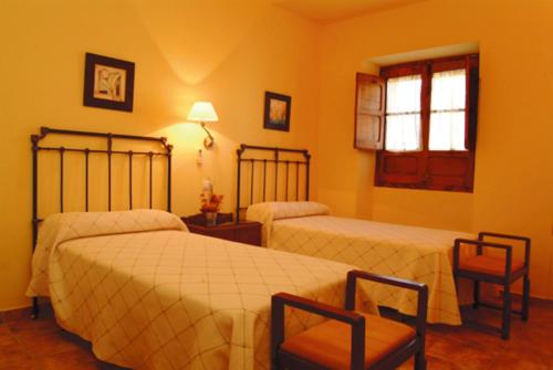 a bedroom with two beds and a chair and a window at Casa Rural Las Avutardas in Sierra de Fuentes