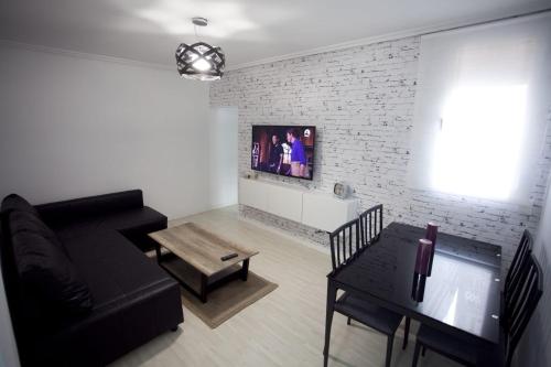 a living room with a black couch and a brick wall at Casa Acosta in Madrid