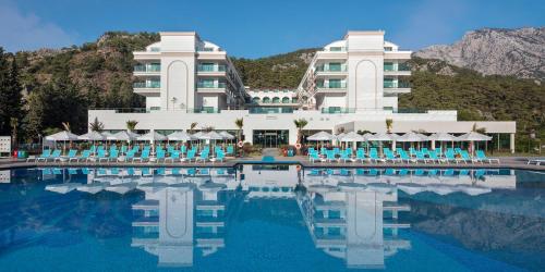 a hotel with a pool with chairs and a building at Dosinia Luxury Resort-Ultra All Inclusive in Beldibi