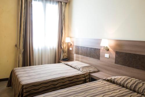 a hotel room with two beds and a window at Hotel Corte Business in Cavriago