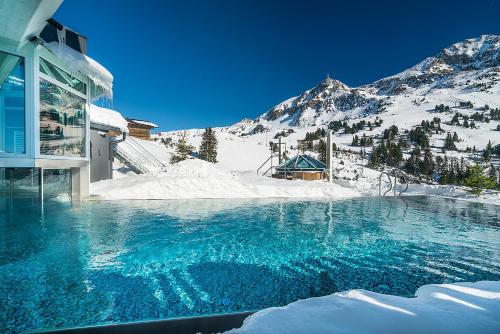 a swimming pool in the snow next to a mountain at Sporthotel Cinderella in Obertauern
