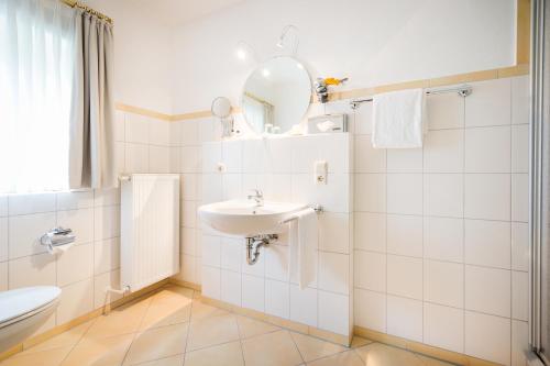 een witte badkamer met een wastafel en een spiegel bij Altes Landhaus Buddenberg in Kleinringe