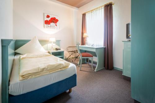 a hotel room with a bed and a desk and a window at Altes Landhaus Buddenberg in Kleinringe