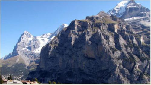 a large rocky mountain with snow on it at Chalet Schönbühl in Mürren