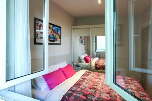 a bedroom with a bed with pink pillows at Apartment Promenada in Novi Sad