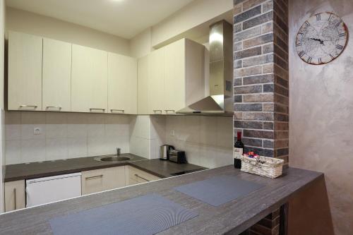 a kitchen with white cabinets and a clock on the wall at Apartment Promenada in Novi Sad