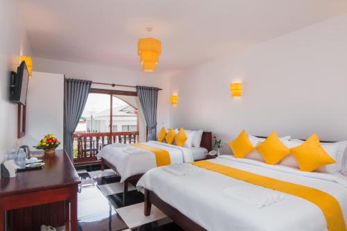 a hotel room with two beds and a balcony at Bou Savy Villa in Siem Reap