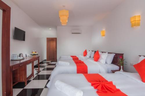a hotel room with two beds with red and white pillows at Bou Savy Villa in Siem Reap