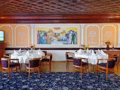 a dining room with tables and chairs and a painting on the wall at Augusta SPA Hotel in Hisarya