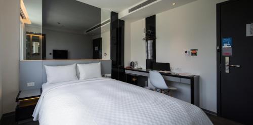 a bedroom with a large white bed and a desk at CityInn Hotel Plus - Taichung Station Branch in Taichung