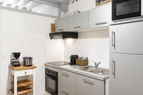 una piccola cucina con armadi bianchi e lavandino di Millesime by Cocoonr a Rennes