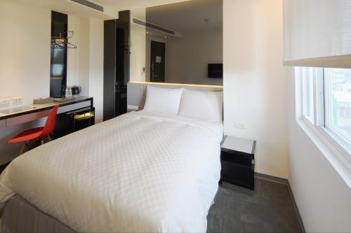 a bedroom with a white bed and a red chair at CityInn Hotel Plus - Taichung Station Branch in Taichung