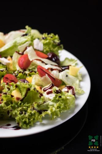 a white plate with a salad on a table at Hotel Pousada do Bosque in Ponta Porã