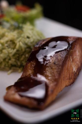 a white plate with a piece of food with sauce at Hotel Pousada do Bosque in Ponta Porã
