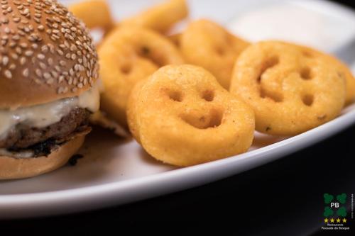 a plate of food with a hamburger and onion rings at Hotel Pousada do Bosque in Ponta Porã