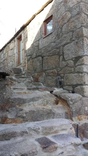 a stone building with stairs leading up to a window at Casa da Avó Ana Alvão in Bilhó