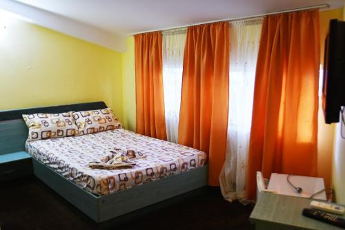 クラヨーヴァにあるPensiunea Nicolasのベッドルーム(ベッド1台、オレンジ色のカーテン付)