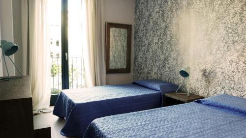 1 dormitorio con 2 camas y ventana en IndispArte Suites en Bergamo