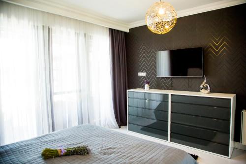 a bedroom with a bed and a dresser with a television at Pensiunea Primaverii in Satu Mare