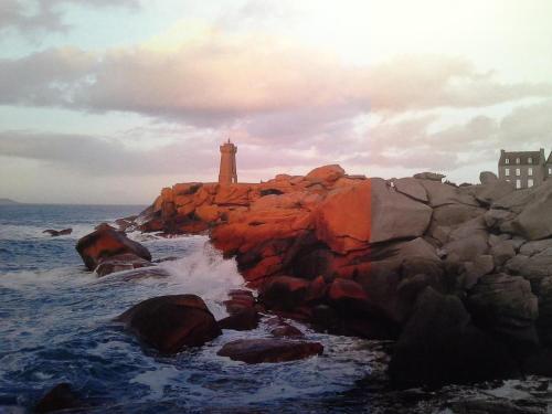 a lighthouse on a rocky shore with the ocean at Parc an Porz in Lannion