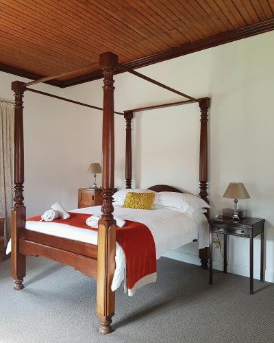 a bedroom with a large bed with a wooden canopy at Wildekrans Country House in Botrivier