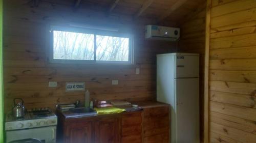 a kitchen with a stove and a refrigerator and a window at Cabañas Sidharta in Tigre