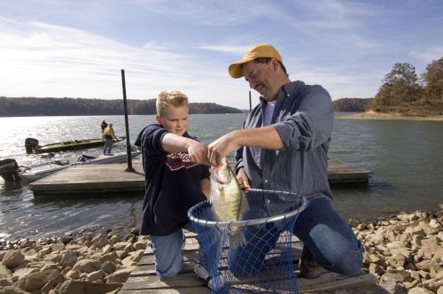 a man and a boy holding a fish in a basket at Kentucky Dam Village State Resort Park in Gilbertsville
