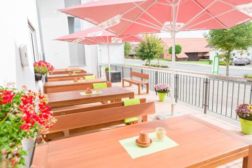 a row of tables and benches with umbrellas on a balcony at Hotel Rhönhof in Hünfeld