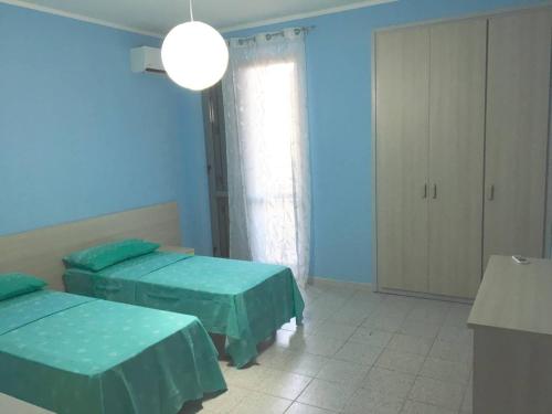 マリーナ・ディ・ジョイオーザ・イオーニカにあるAppartamento Vacanzeの青い壁の客室で、ベッド2台が備わります。