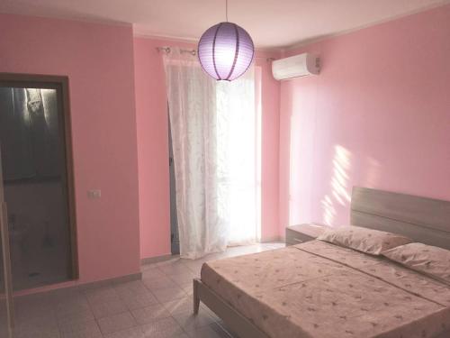 マリーナ・ディ・ジョイオーザ・イオーニカにあるAppartamento Vacanzeのピンクの壁、ベッド1台付きのベッドルーム1室