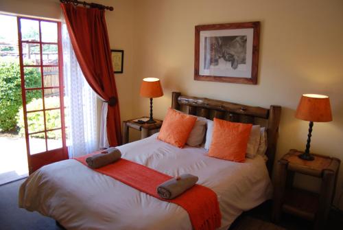 ein Schlafzimmer mit einem Bett mit orangefarbenen Kissen in der Unterkunft Journey's Inn Africa Guest Lodge in Kempton Park