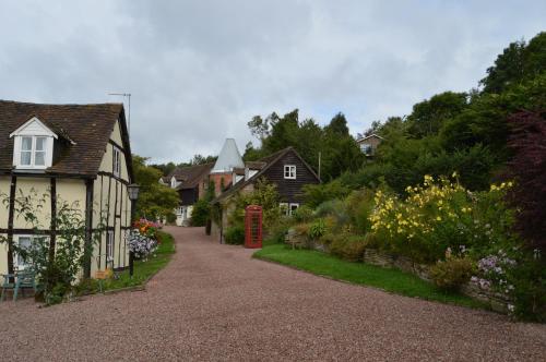 a street with houses and a red phone booth at Whitewells Farm Cottages - 7 exceptionally well appointed pet friendly barn conversions set in 10 acres of gardens, fields and woodland suitable from 2 to 24 people with breathtaking views towards the Malvern Hills, Herefordshire and Worcestershire in Mathon