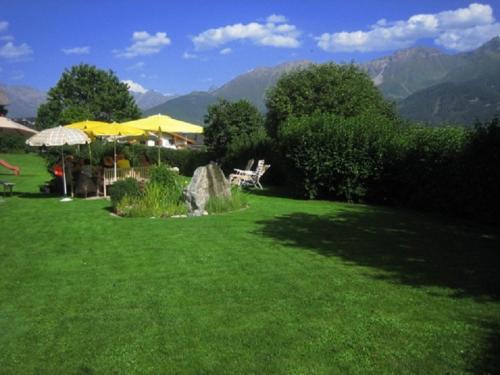 a green lawn with umbrellas and chairs on it at Apart Daniela in Fiss