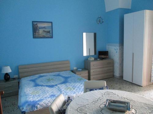 カザラーノにあるAzzurro Cieloの青い壁のベッドルーム1室、ベッド1台、テーブルが備わります。