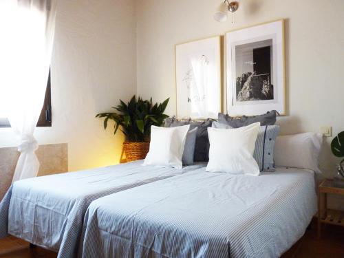 a bedroom with a large bed with white sheets and pillows at Casa Rural Cabeza Lobera in Villanueva de Ávila