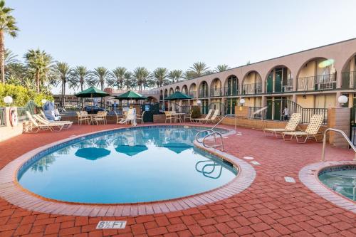 a pool at a resort with tables and chairs at Kings Inn Anaheim at The Park & Convention Center in Anaheim