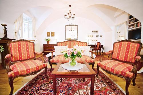 una sala de estar con 2 sillas y una mesa con un jarrón de flores en Salzburg Place to Stay, en Salzburgo
